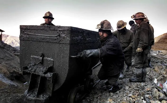 Mineros bolivianos trabajando con vagoneta de mineral