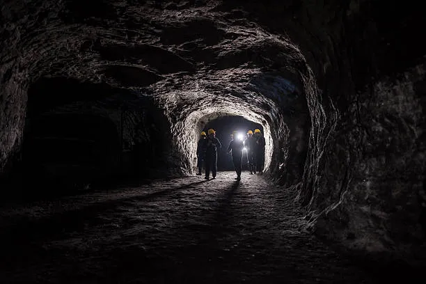 Mineros en túnel subterráneo con cascos y lámparas
